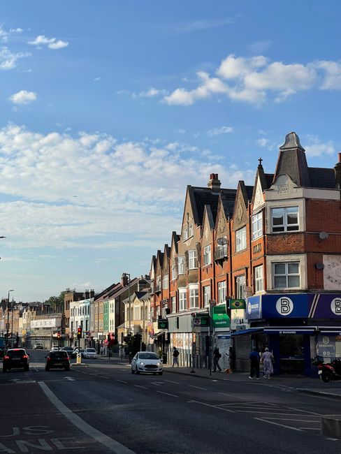 The image shows a street scene on High Road in N20, featuring a line of traditional red brick Victorian-style houses with steeply pitched roofs and decorative gables. Storefronts at street level inclu